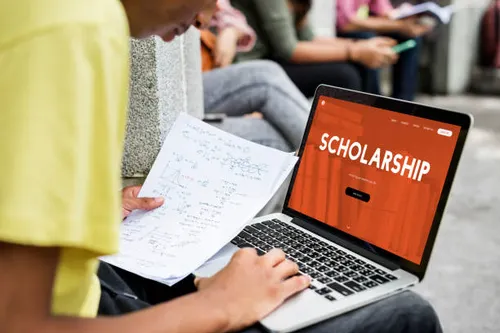 Student researching scholarship opportunities on a laptop